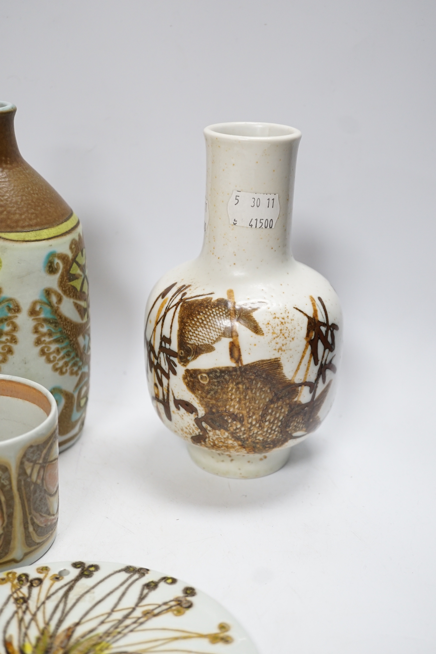Seven Royal Copenhagen fajance items; a vase decorated with birds, a vase, decorated with fish, a small pot, a holder, two circular dishes and a teapot stand, largest dish 26cm diameter